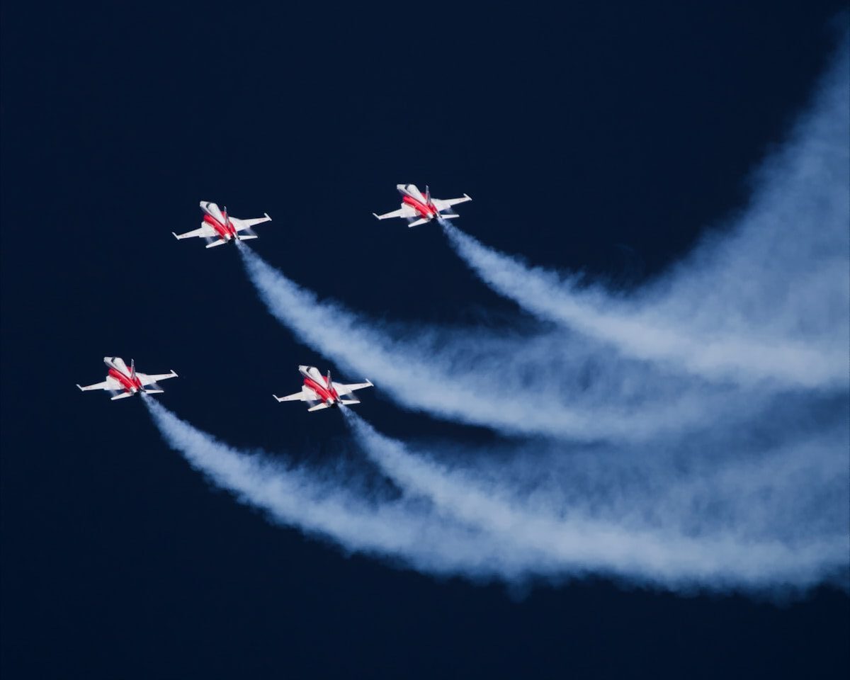 Five fighter jets flying with smoke trails in dark sky.